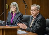 Steve Morse sits at the testifiers' table and speaks to someone out of view. Representative Klevorn sits next to him and looks in the same direction.